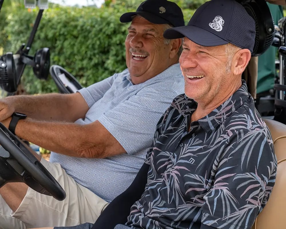 two male golfers in cart laughing